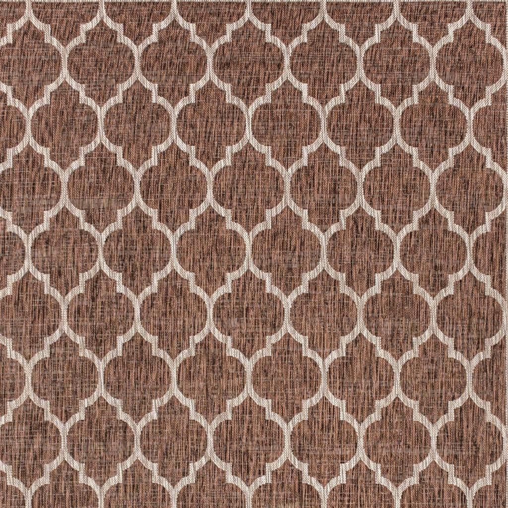Close-up geometric indoor outdoor rug in espresso brown with taupe linked shapes