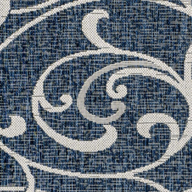 Navy blue rug close-up with cream swirl floral pattern and woven texture