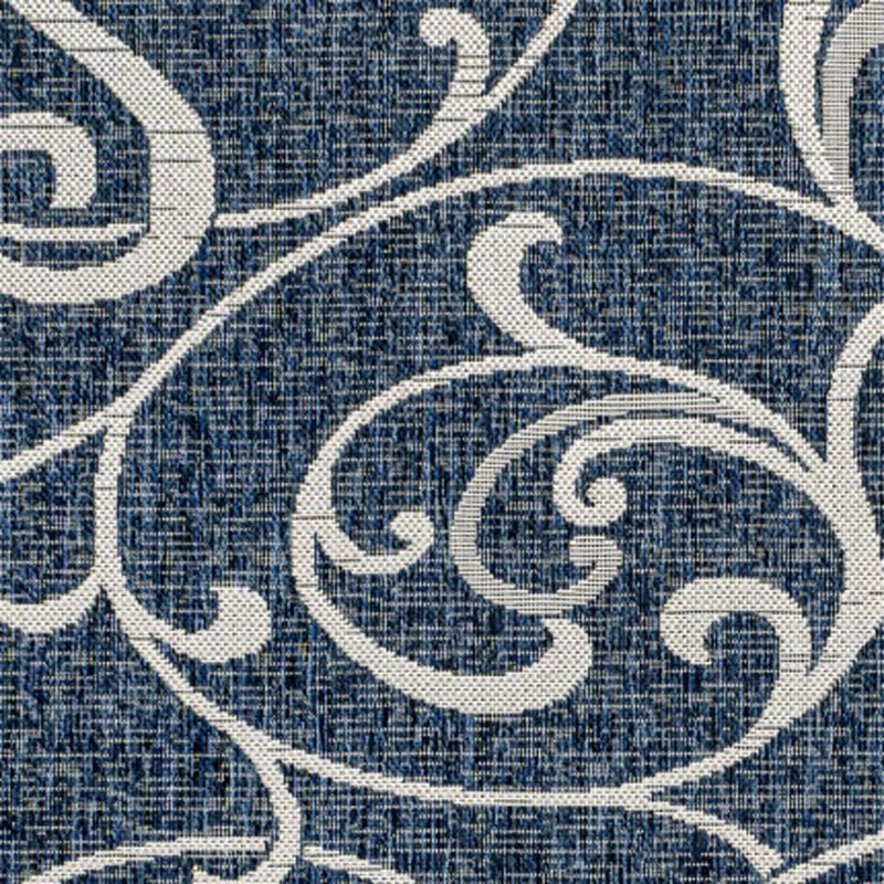 Navy blue rug close-up with cream curved scrolls and textured fibers