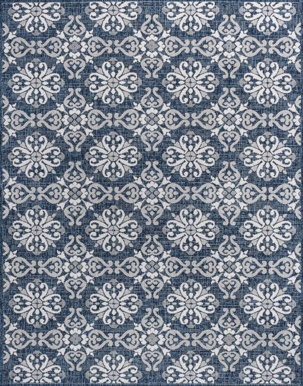 Close-up of navy and cream floral area rug with repeating damask motifs.