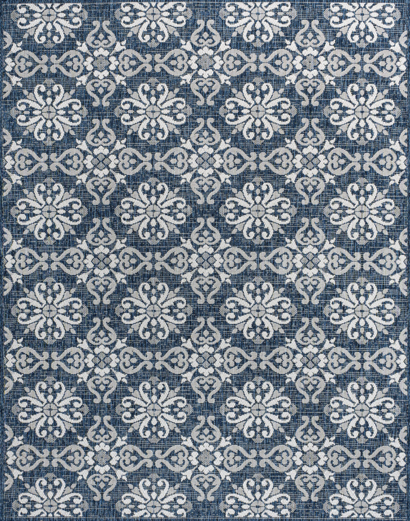 Close-up of navy and cream floral area rug with repeating damask motifs.