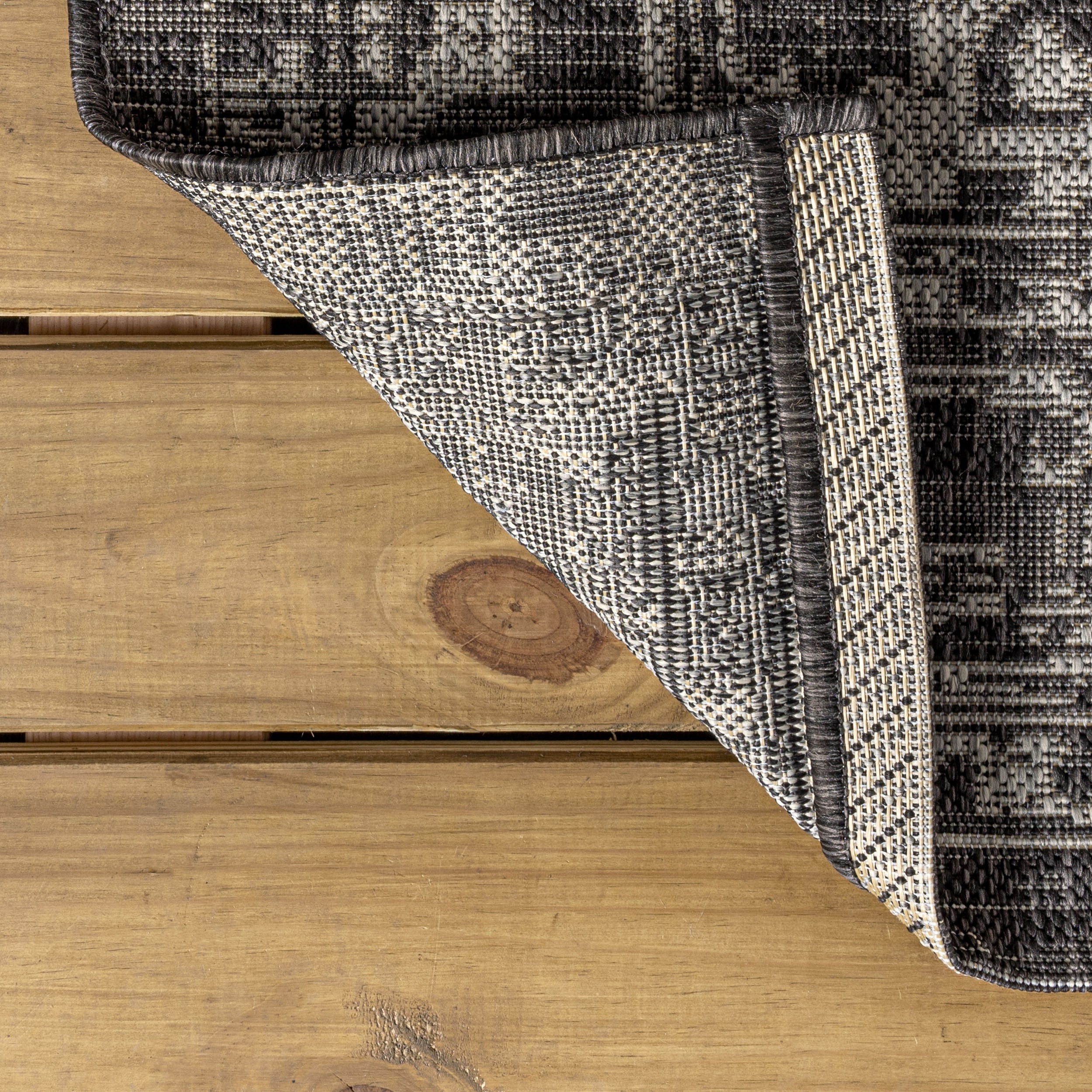 Black and gray patterned area rug with stitched edge detail