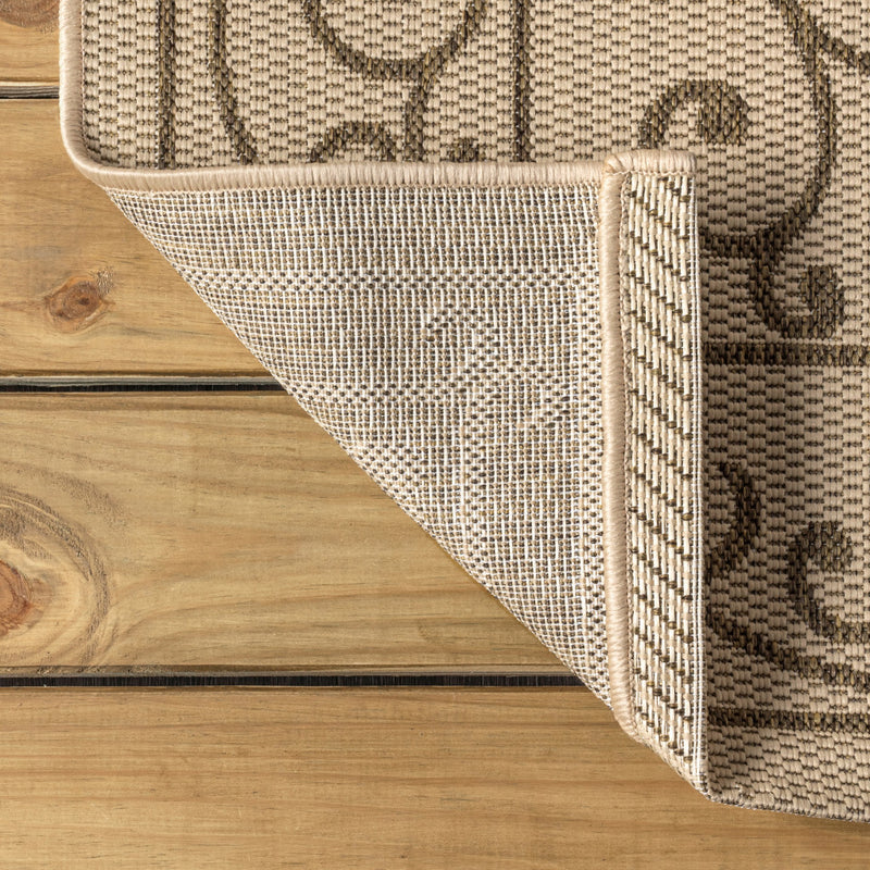 Corner view of round beige and brown rug with stitched edge and geometric trim