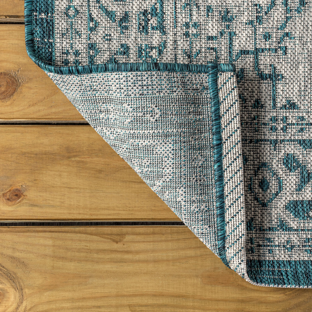 Round area rug corner view with teal blue and gray medallion pattern and teal binding