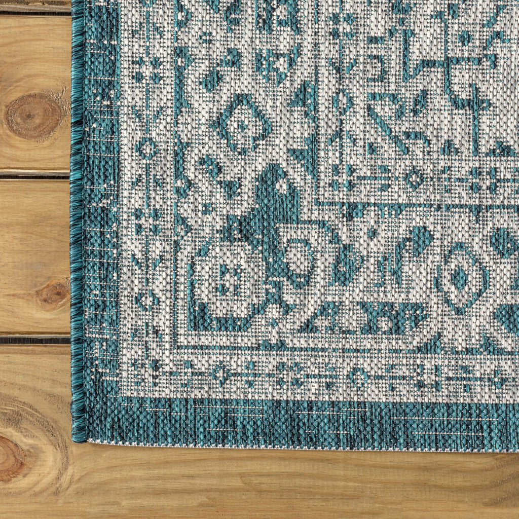 Rectangular corner section of round area rug with teal blue and gray medallion motif