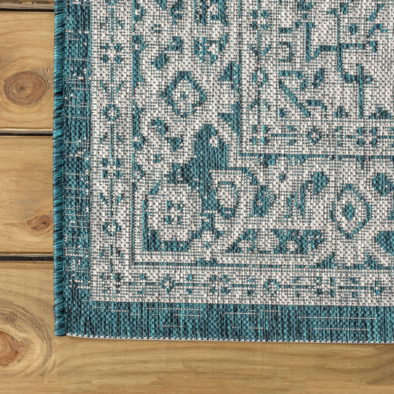 Rectangular corner section of round area rug with teal blue and gray medallion motif
