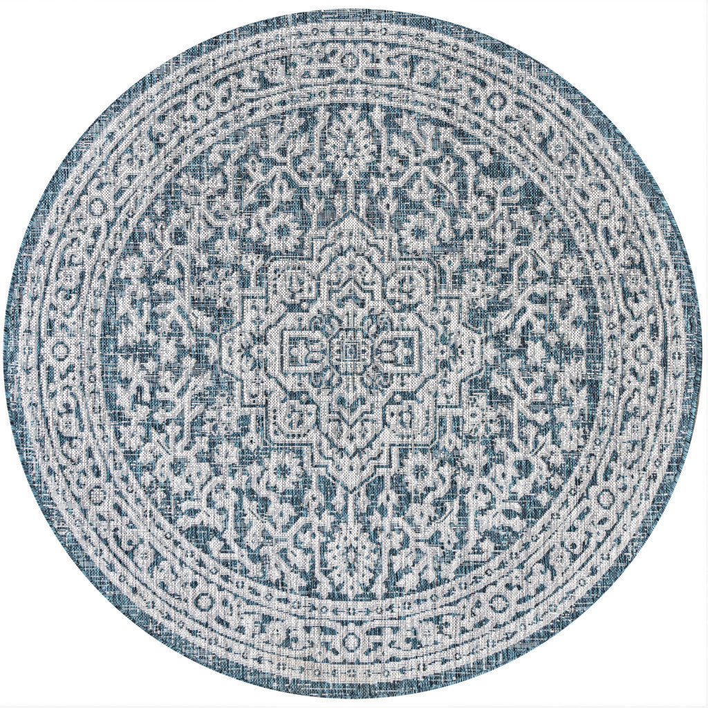 Round area rug with light blue and gray medallion pattern and teal-trimmed border