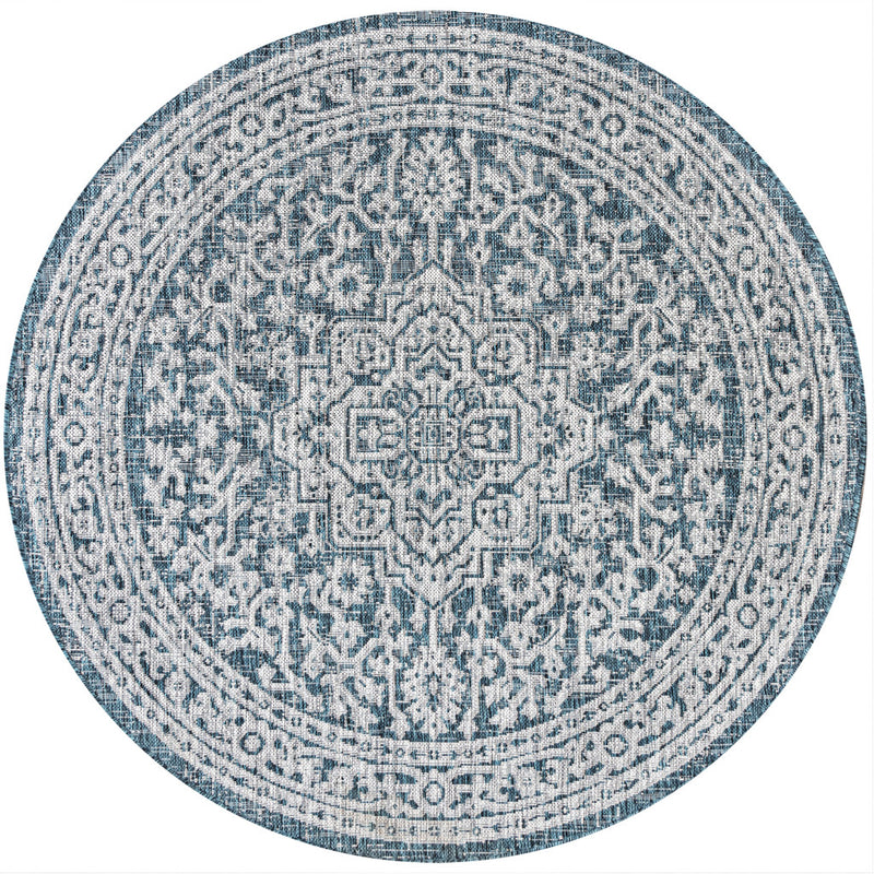 Round area rug with light blue and gray medallion pattern and teal-trimmed border