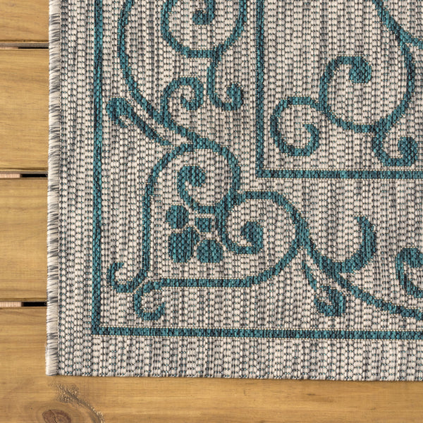 Square area rug with gray ground and teal ornate scrollwork medallion design.