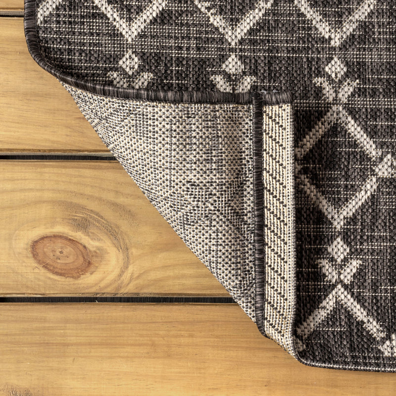 Round black and gray trellis area rug corner with braided trim and border stripe
