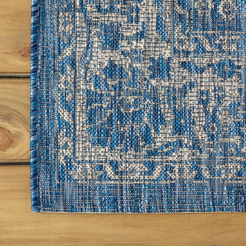 Close-up of blue and ivory distressed medallion pattern with bordered border at corner