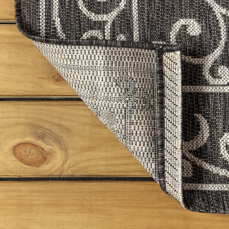 Corner view of round area rug showing edge binding and dark gray woven texture