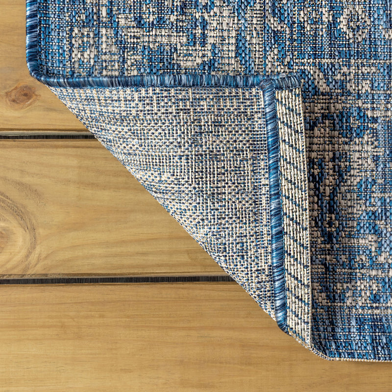 Corner view of navy and gray rug showing border stripes and patterned flatweave