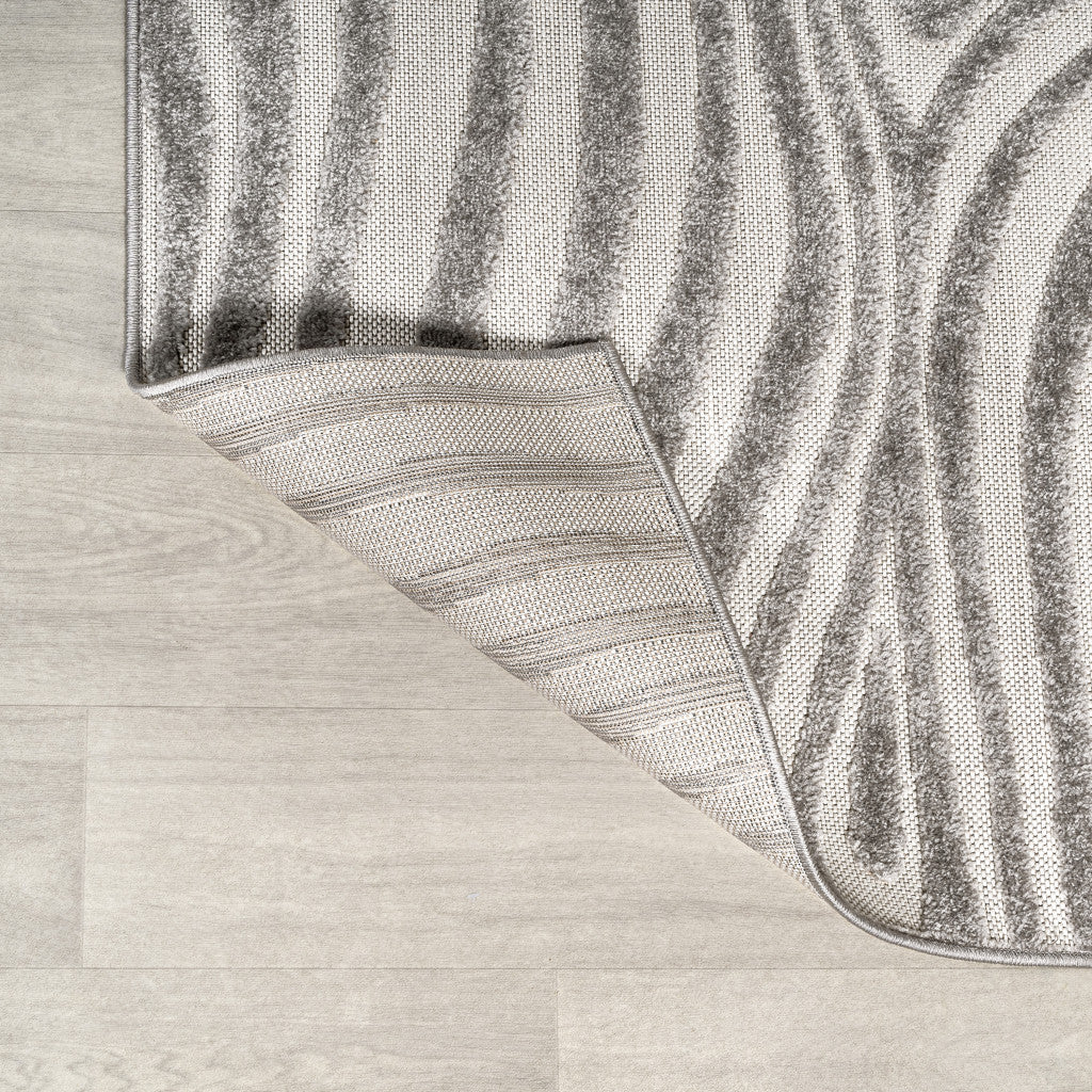 Gray and ivory area rug corner with rounded bound edge and visible backing