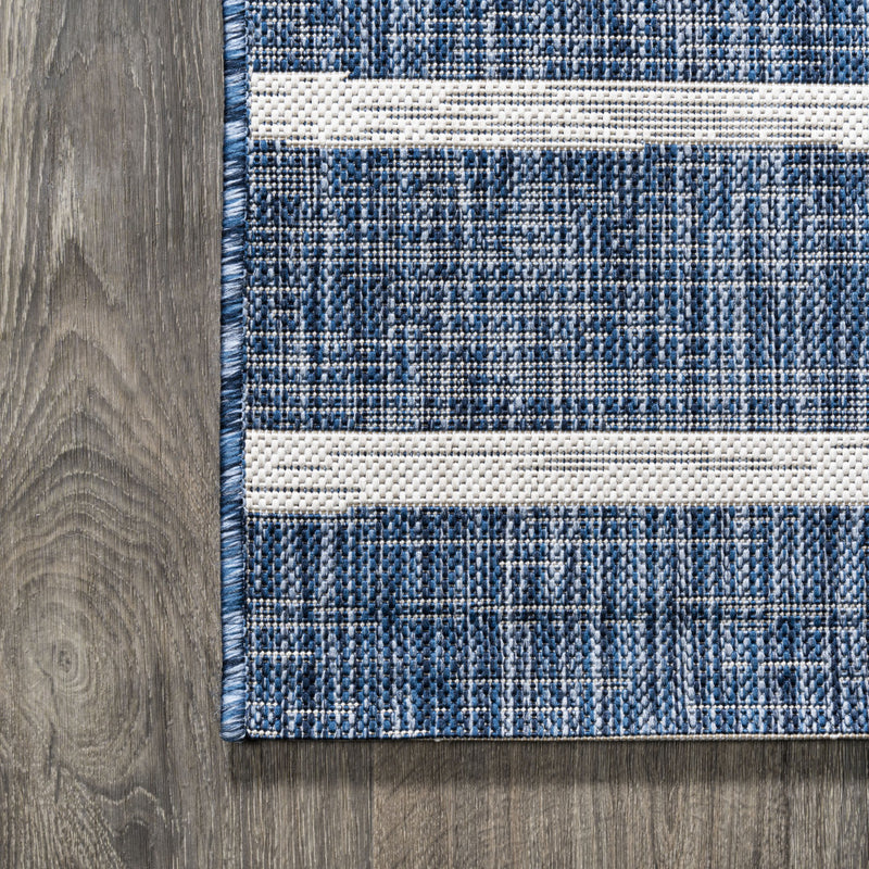 Blue and ivory striped area rug corner on wood floor, showing flat woven texture