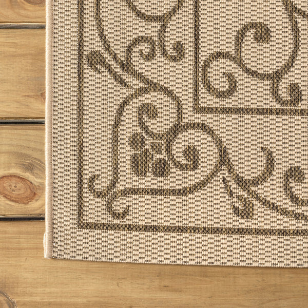 Beige rug edge with brown medallion motif and patterned border strip near the corner.