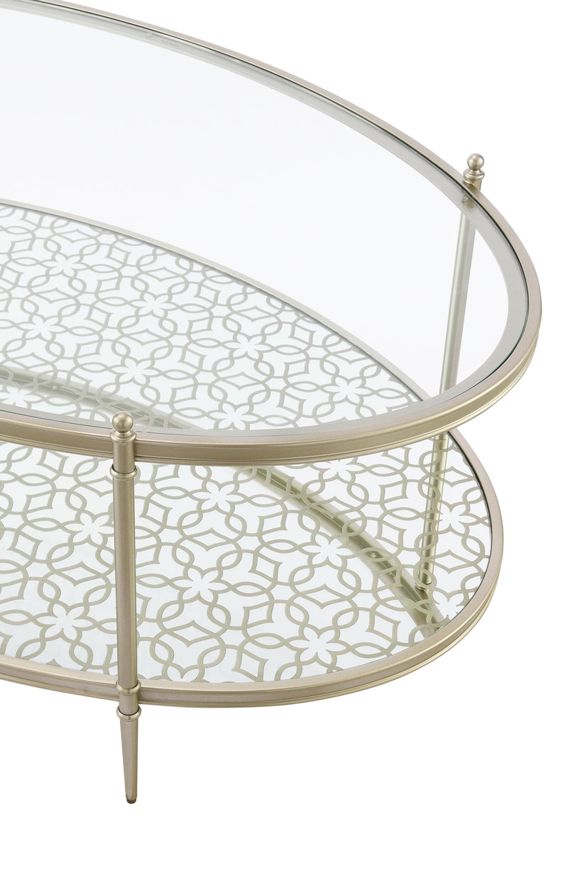 Angled view of oval clear glass coffee table with patterned lower shelf and champagne legs