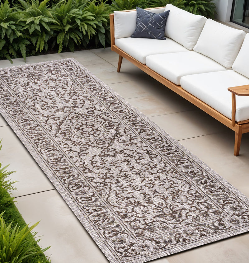 Brown and beige medallion indoor outdoor runner rug laid on patio tiles.