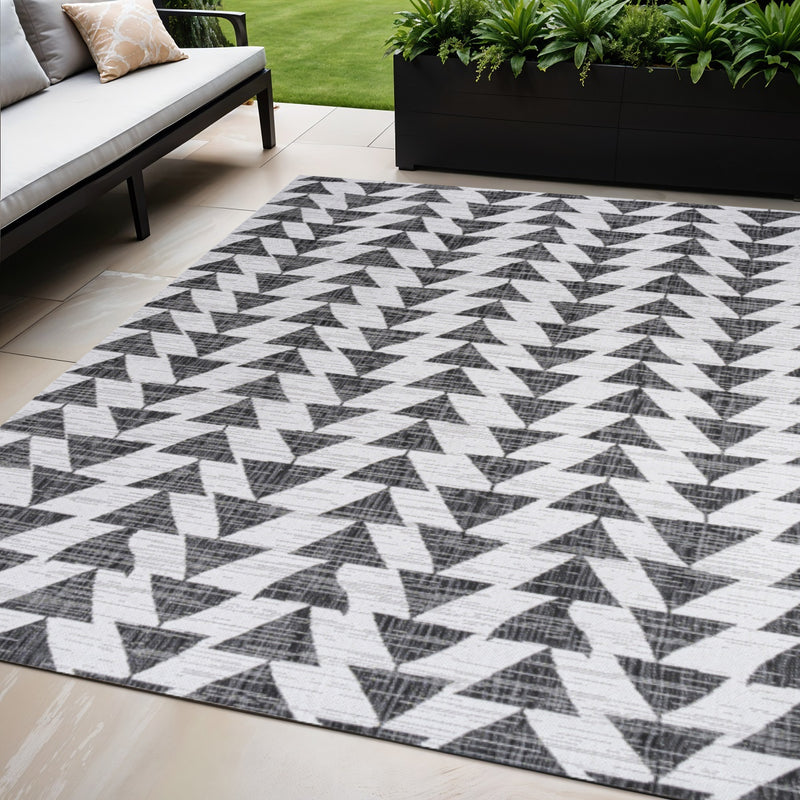 Geometric indoor outdoor area rug with ivory base and black zigzag triangle design.