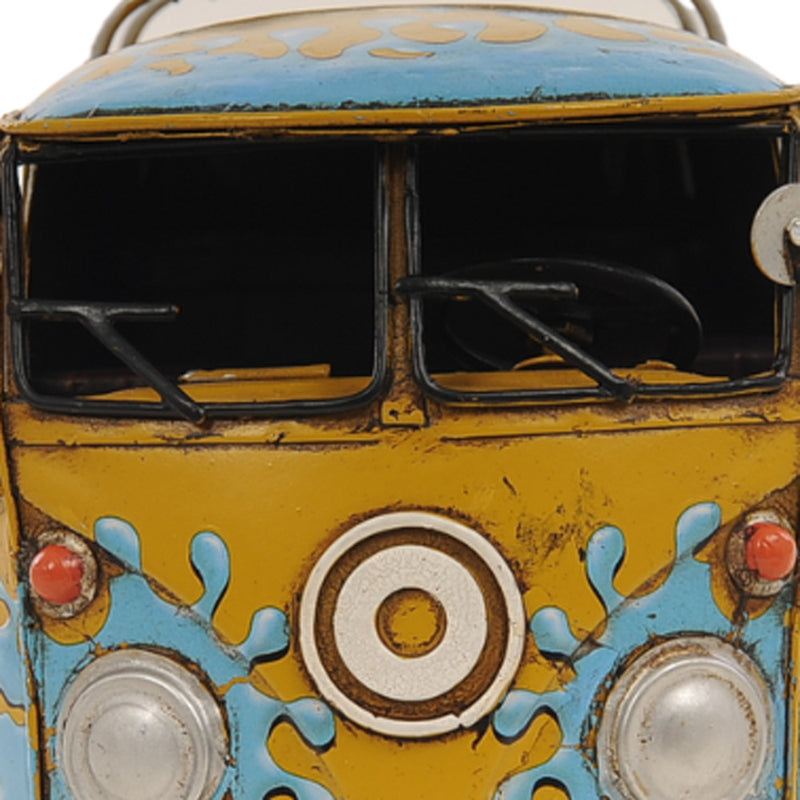 Close-up of yellow metal van front with blue splash paint and circular headlight accents.