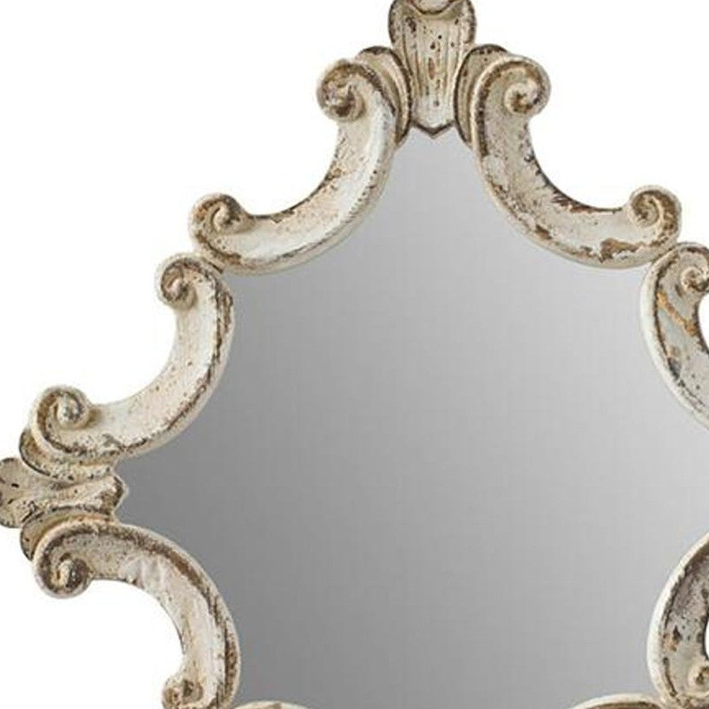 Accent mirror close-up: distressed white ornate wood frame, carved scrolls and fleur-de-lis