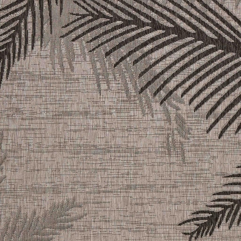 Beige indoor/outdoor rug close-up with dark gray palm frond pattern on woven texture