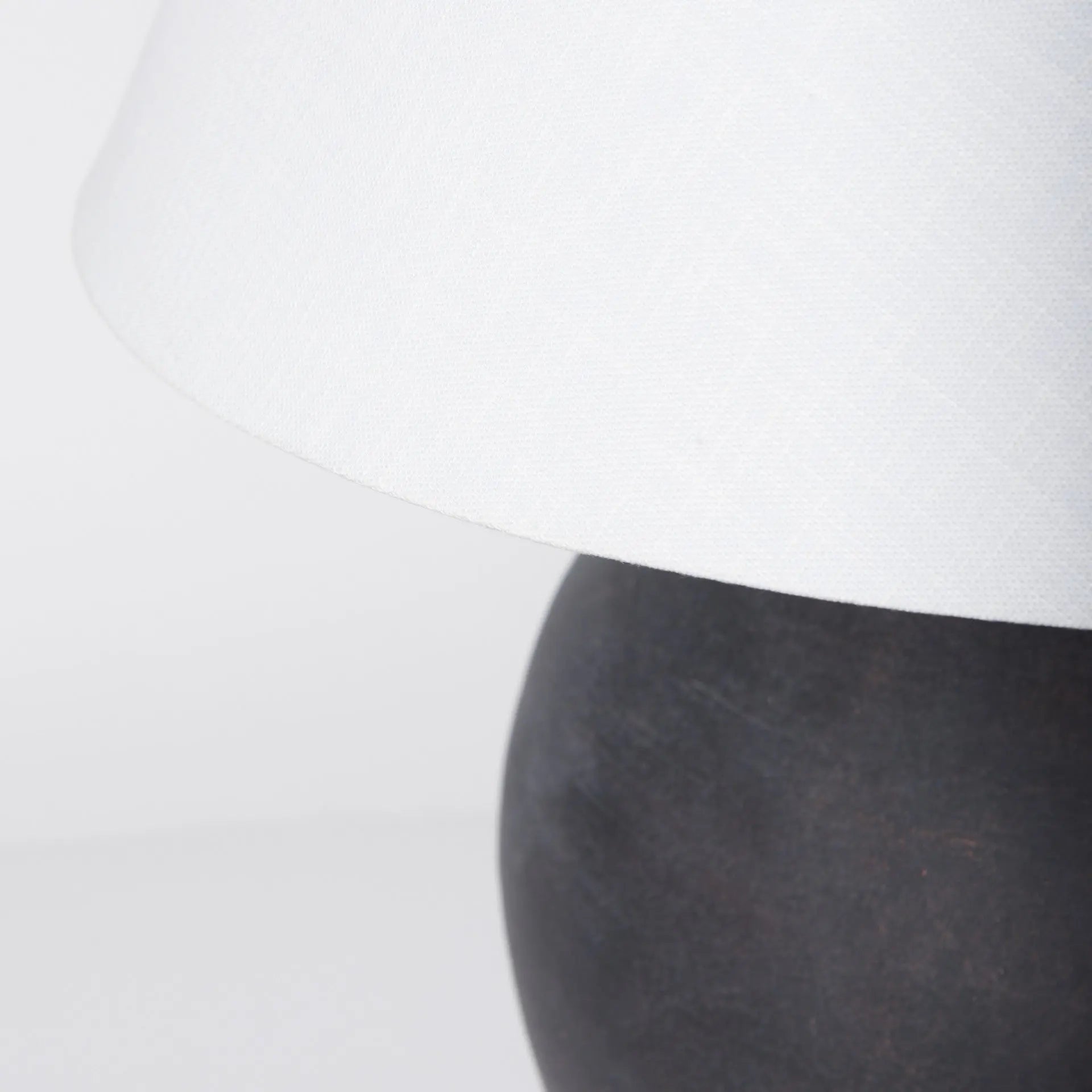 Black ceramic table lamp with a textured finish and a white linen shade, adding modern elegance to any space.