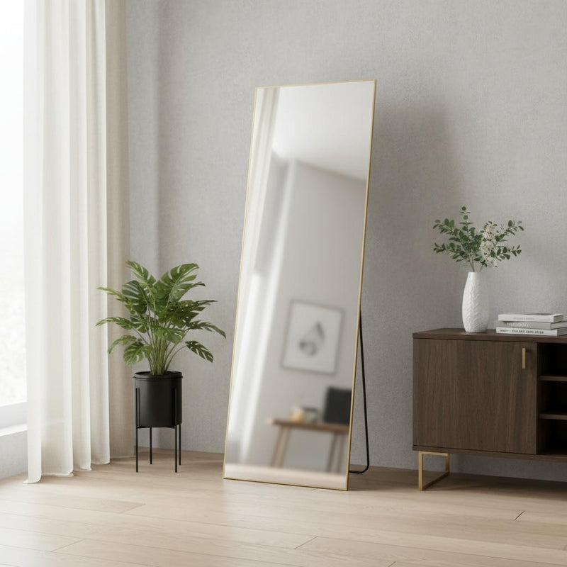 Gold framed standing mirror with reflective glass, placed on the floor