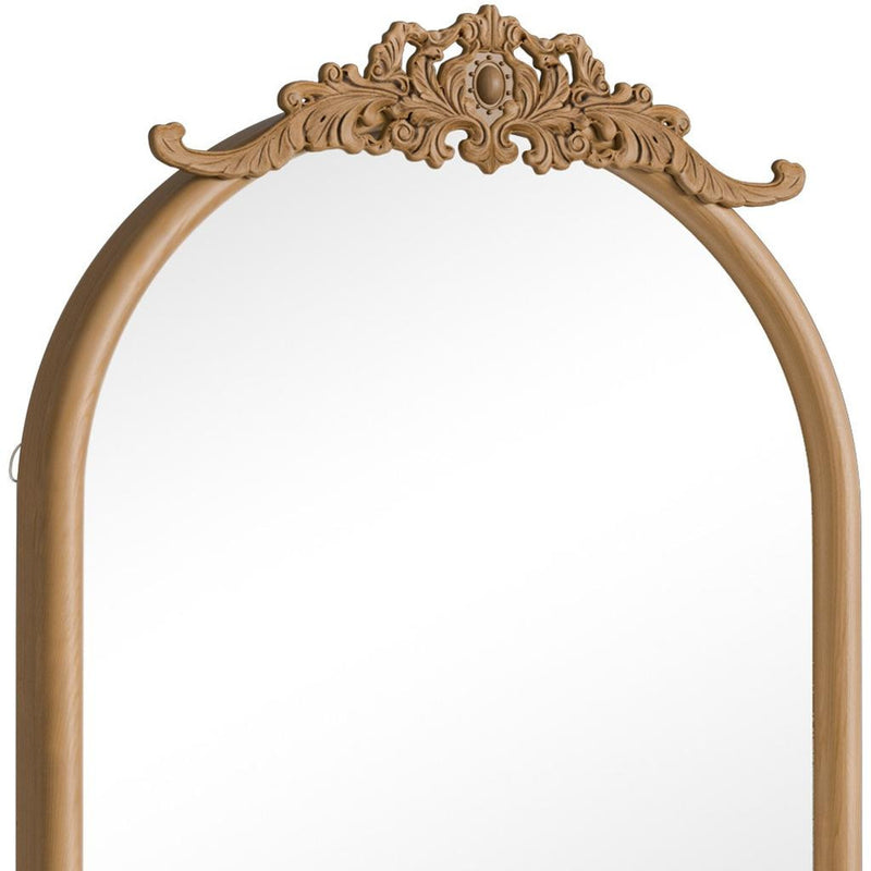 Close-up of arched mirror top with brown carved scrollwork frame
