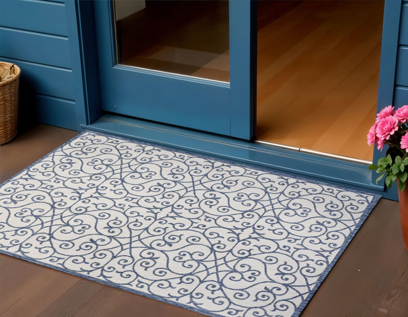 Blue and cream geometric area rug with ornate swirl design, shown on hardwood floor