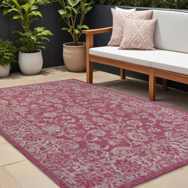 Fuchsia medallion area rug with ornate distressed pattern, set on patio