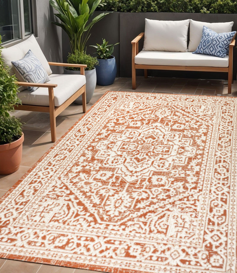 Orange and cream medallion indoor/outdoor area rug with bordered geometric pattern