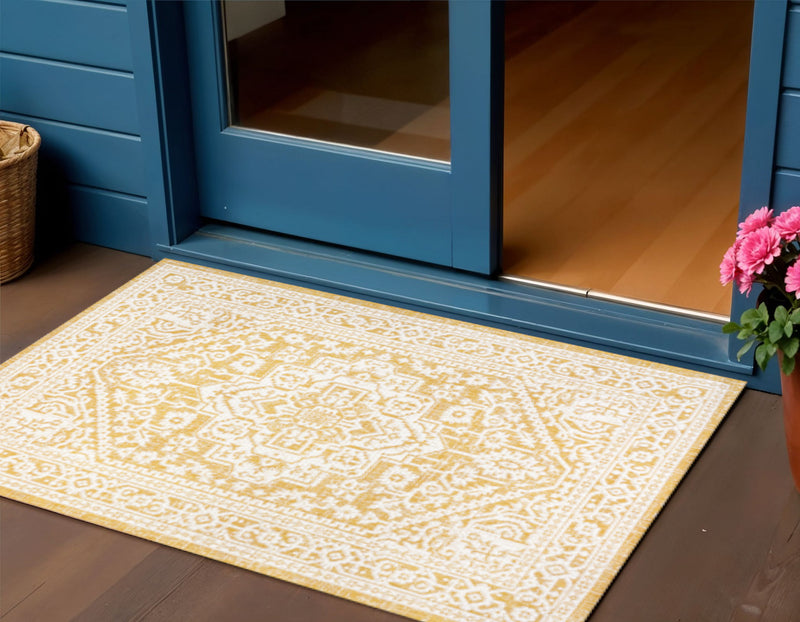 Yellow and cream patterned area rug laid on floor near doorway, indoor outdoor style.
