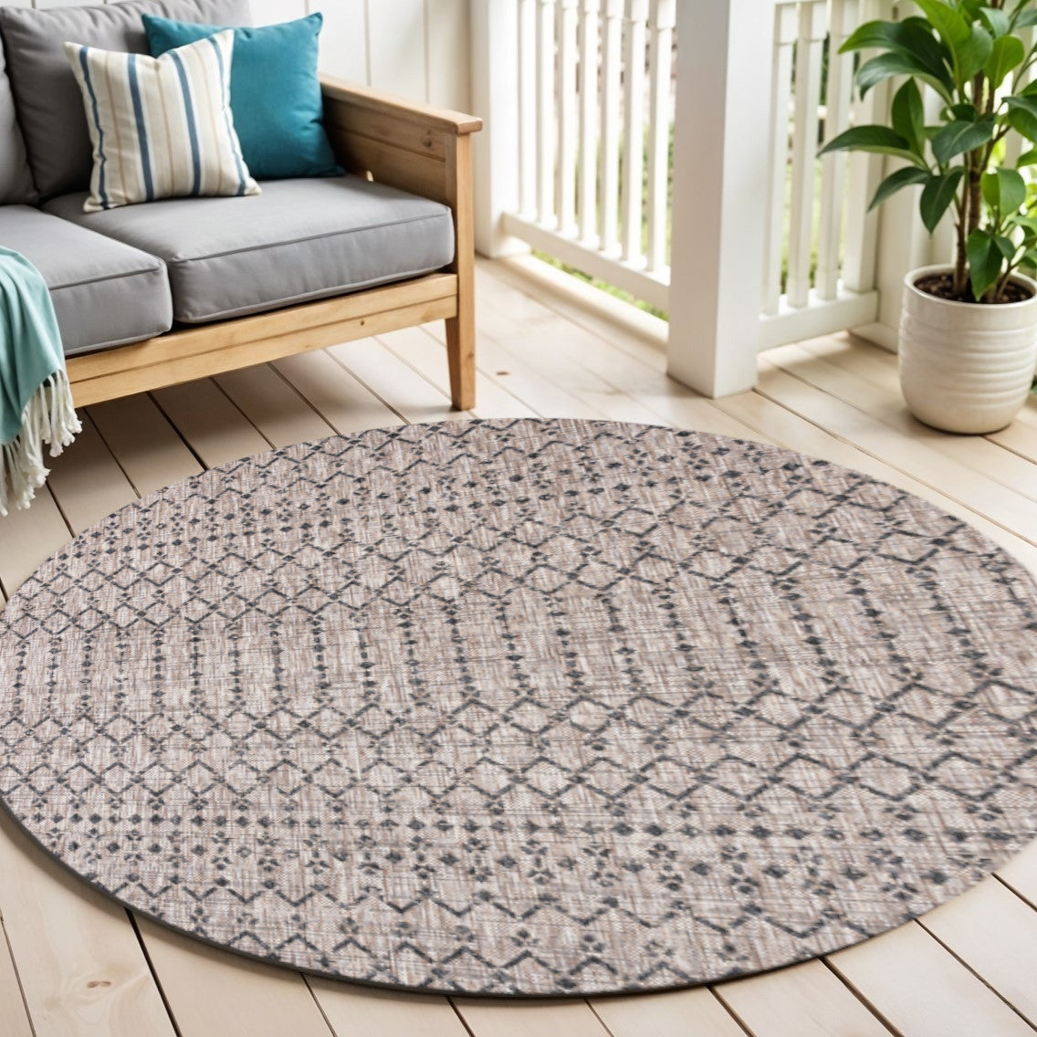 Round trellis area rug in beige with black diamond pattern in living room setting.
