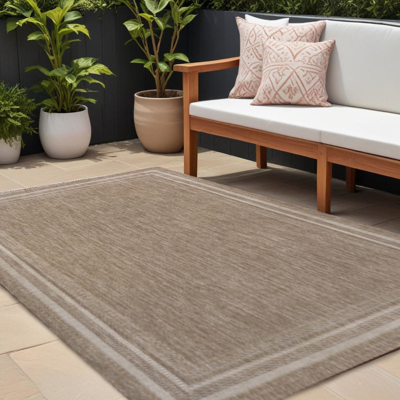 Beige and cream area rug laid on patio with simple border and textured surface