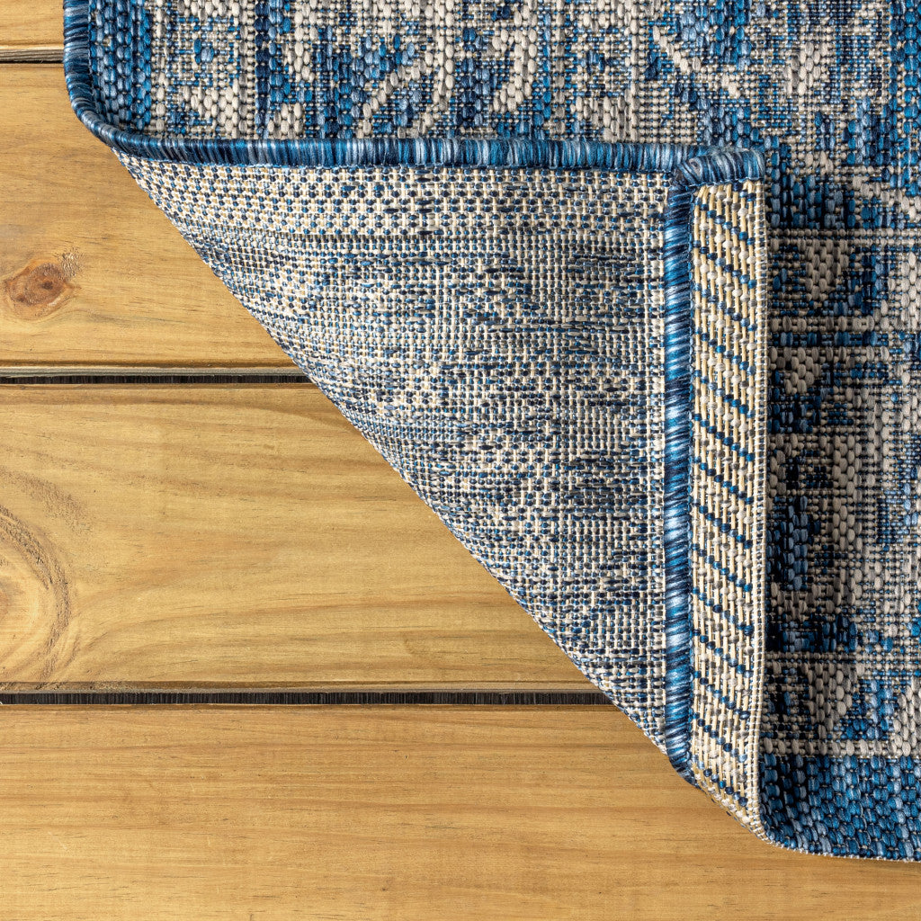 Navy and gray medallion area rug edge with stitched border and textured pile