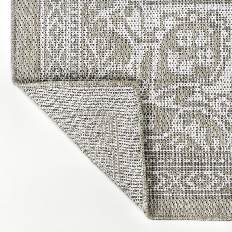 Beige and cream patterned area rug showing woven texture and stitched edge