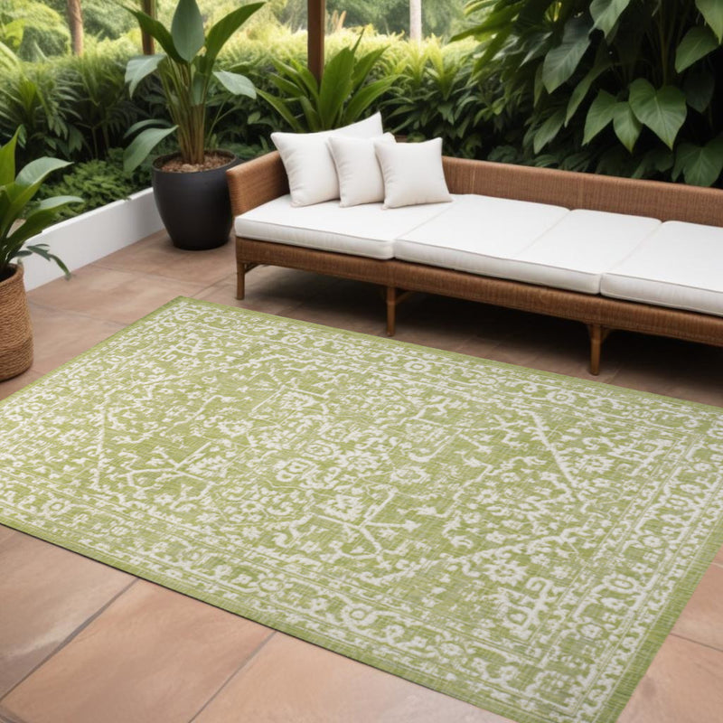 Green and cream medallion area rug on floor, wide border and central motif
