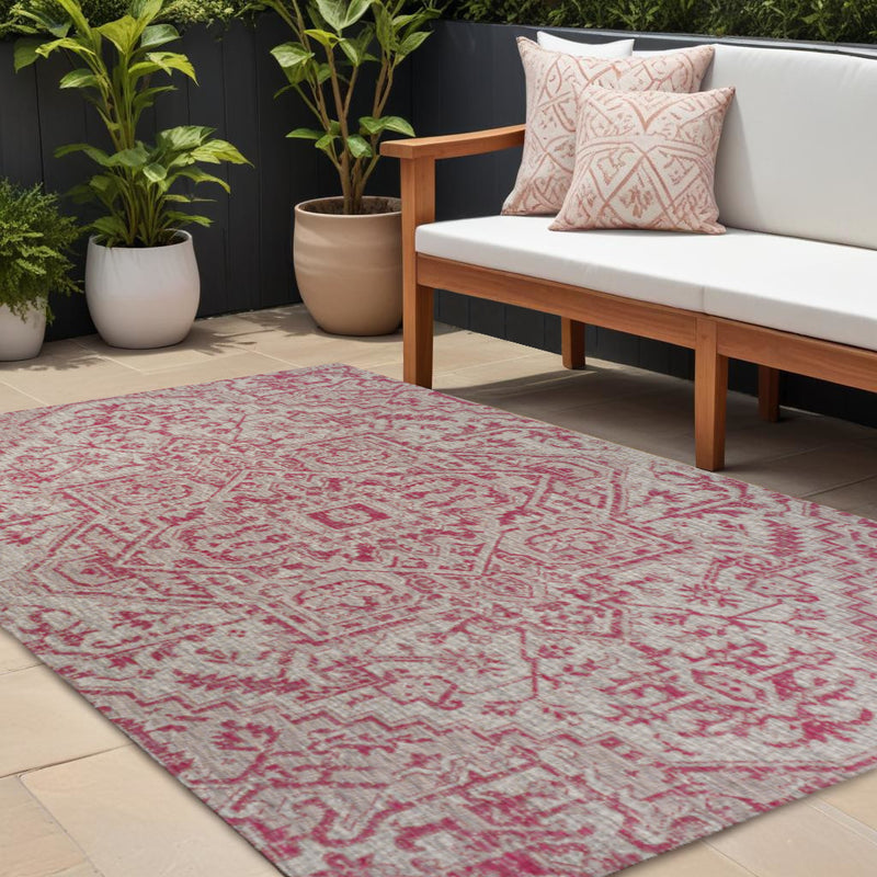 Indoor outdoor area rug with red medallion pattern laid on patio tile flooring