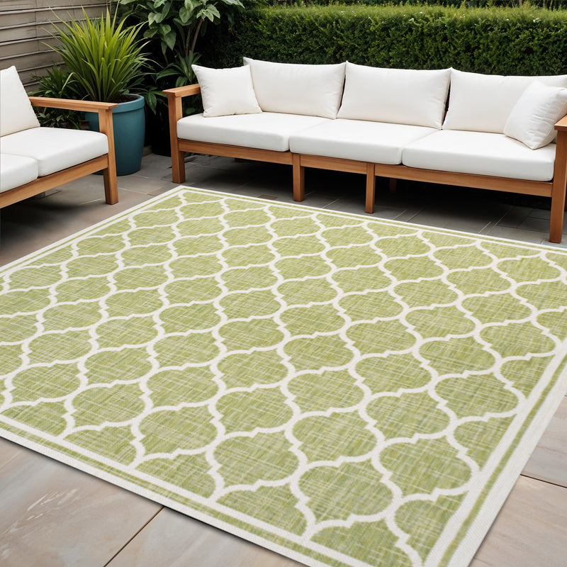 Green and cream quatrefoil geometric square area rug on outdoor patio flooring.