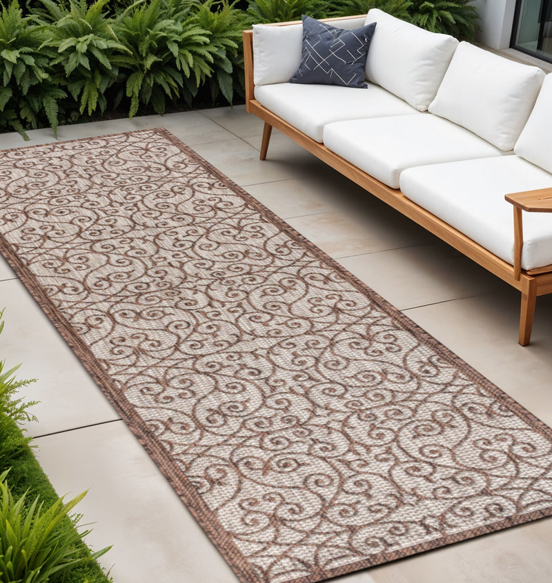 Taupe and espresso geometric indoor outdoor runner rug with swirl pattern and bordered edges.