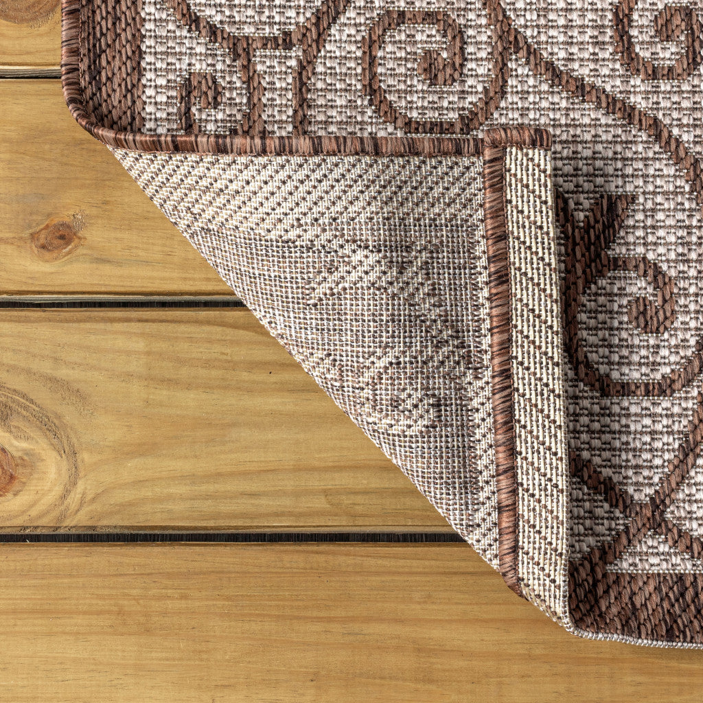 Taupe and espresso geometric runner rug corner with braided border and diamond medallion pattern.