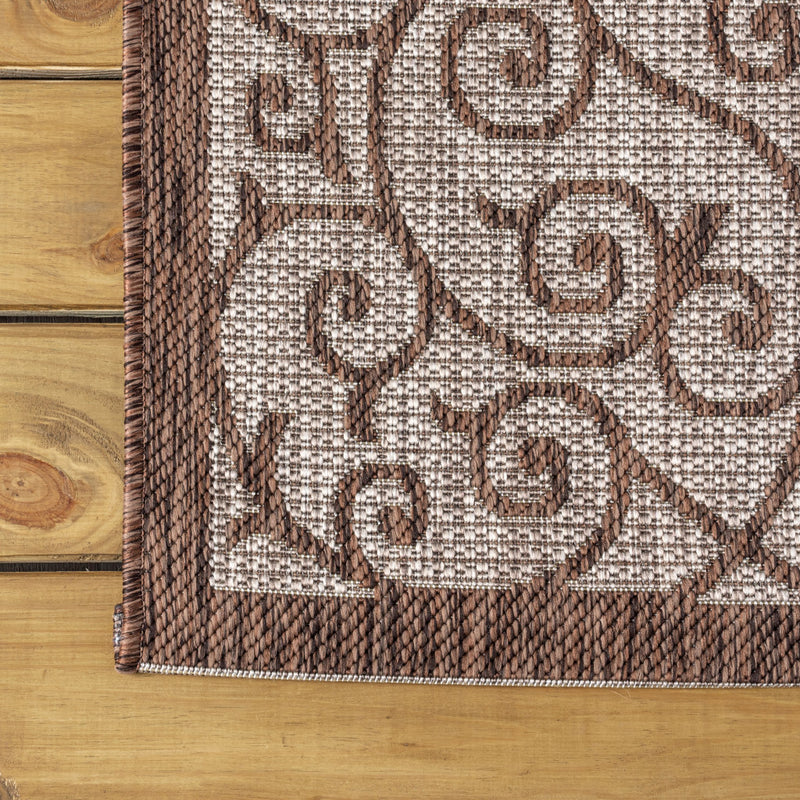 Taupe and espresso geometric rug close-up with circular medallion motifs and fringe trim.