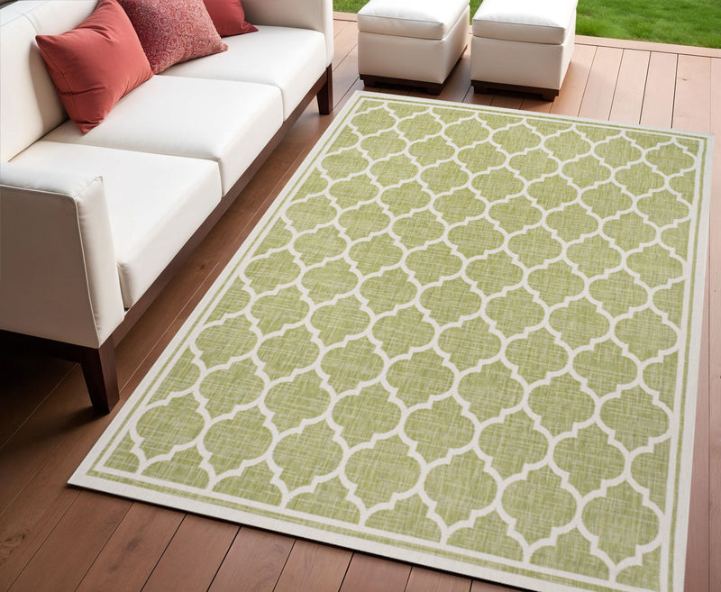 Green and cream geometric area rug on wooden floor beside outdoor seating