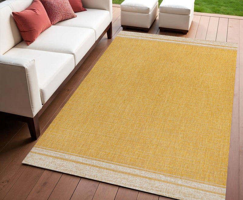Rectangular yellow area rug with cream border, flat woven texture in patio setting
