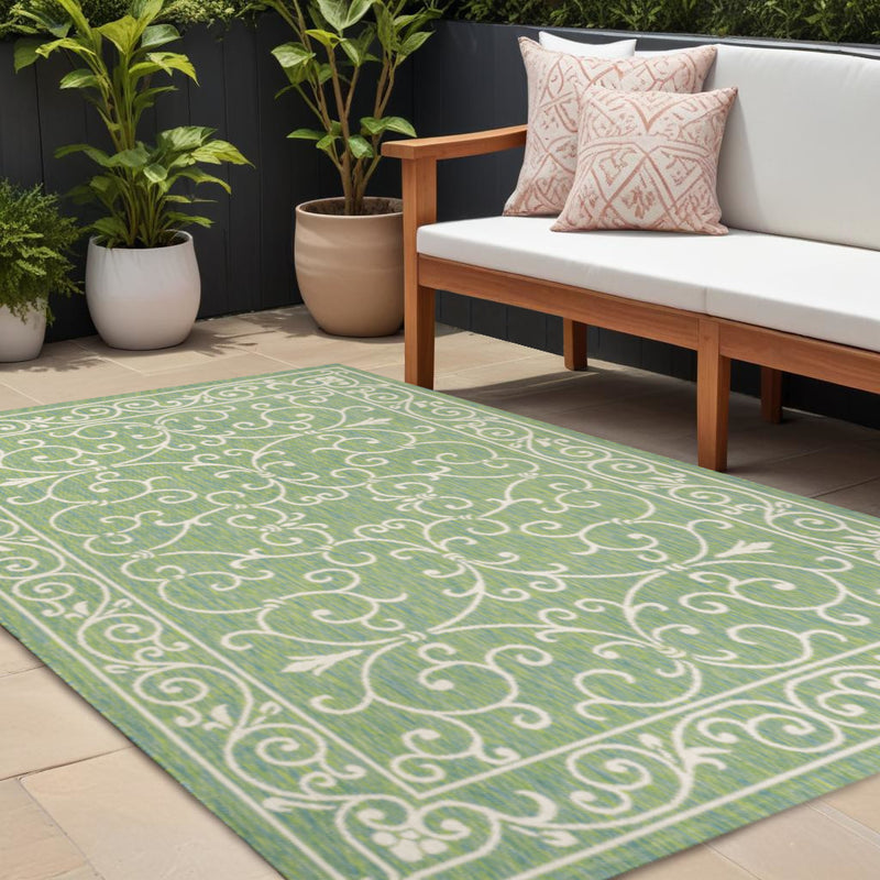 Green area rug with ivory medallion scroll pattern
