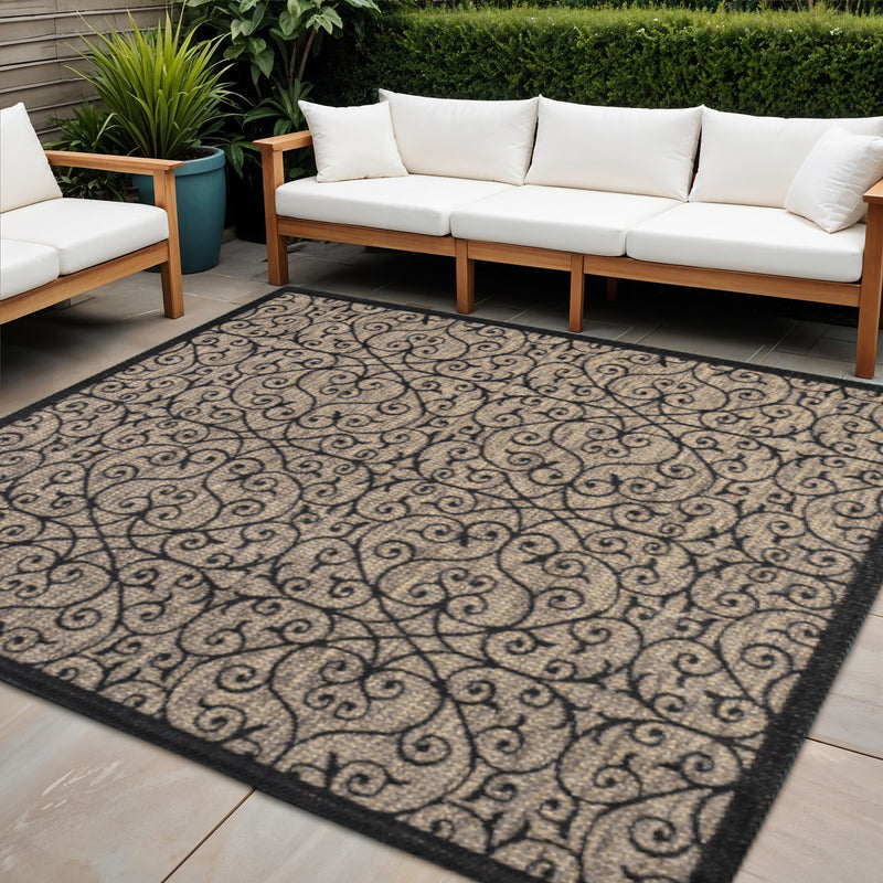 Indoor outdoor area rug with ornate geometric scroll pattern and dark border