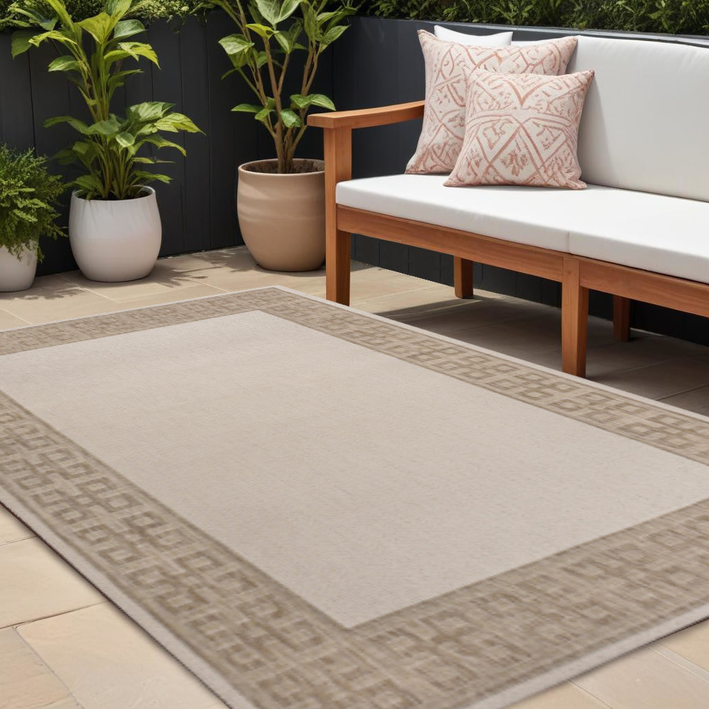 Cream and beige outdoor area rug with Greek key border, laid on patio
