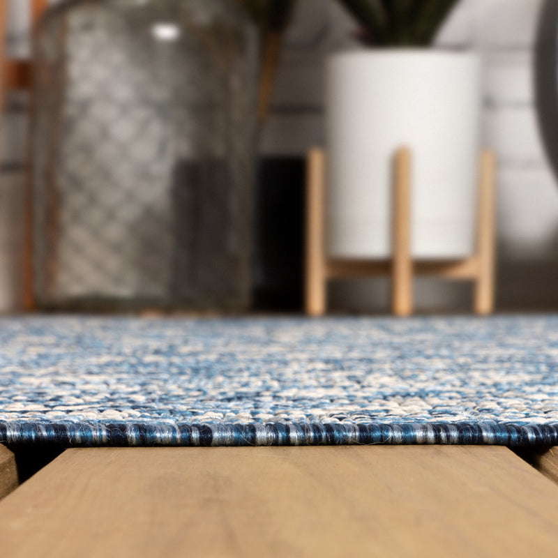 Round blue-and-gray rug edge with low pile texture and navy-and-white woven border