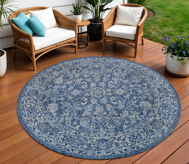Round blue-and-gray medallion outdoor rug with detailed pattern on wooden patio
